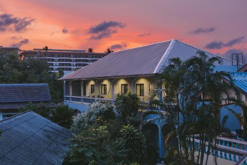 a house with a roof with a sunset in the background at Fantasy Hill Bungalow in Kata Beach
