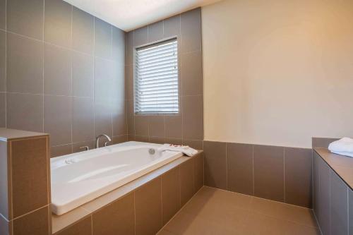 a bathroom with a tub and a window at Baymont by Wyndham Tri-Cities/Kennewick WA in Kennewick