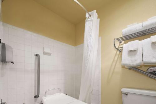a bathroom with a shower and a toilet and towels at Days Inn & Suites by Wyndham Stevens Point in Stevens Point