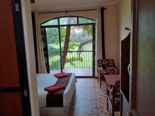 Schlafzimmer mit einem Bett und einer Tür zu einem Balkon in der Unterkunft Country View Cottage Colva in Colva