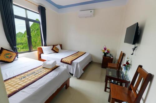 a hotel room with two beds and a tv at Son Doong Riverside in Phong Nha