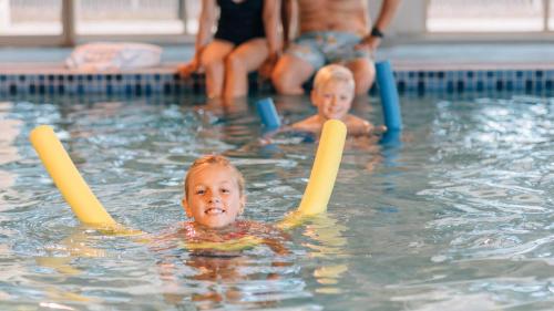 zwei Kinder spielen in einem Pool mit Stöcken in der Unterkunft Country Club Villas in Launceston