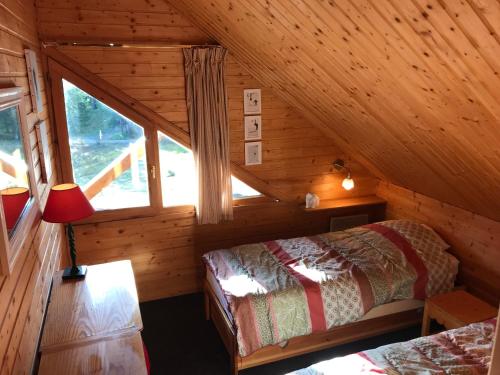 Cette chambre mansardée comprend un lit et une fenêtre. dans l'établissement Appartements duplex dans chalet - Pléiades -, skis aux pieds avec clefs à disposition via agence constel'immo -nous louons aussi le second duplex du chalet quasiment identique, à Risoul