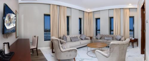 a living room with couches and a table and windows at Muscat Gate Hotel in Muscat