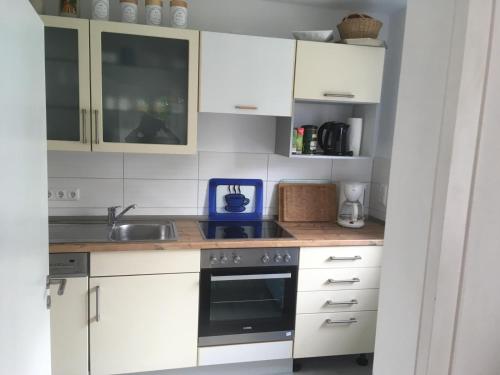 Una cocina con gabinetes blancos y un horno de estufa. en Ferienhaus am Schloss, Haag 127, en Aufseß
