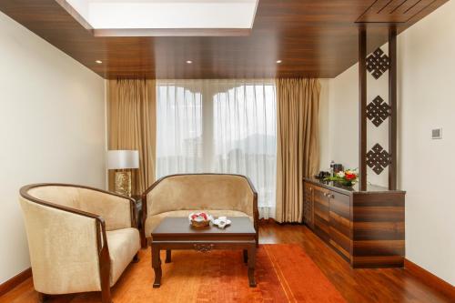 a living room with a chair and a table at Ramada by Wyndham Kathmandu Dhumbarahi in Kathmandu