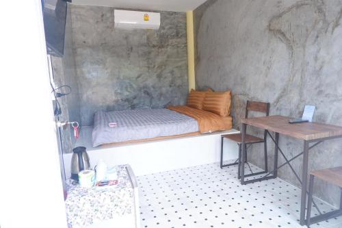 a small bedroom with a bed and a table at Baanpak Jomyutt Suan Phueng in Suan Phung