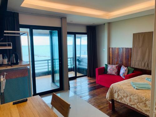 Habitación con cama, sofá rojo y balcón. en Petit Suncliff Resort, en Haad Rin