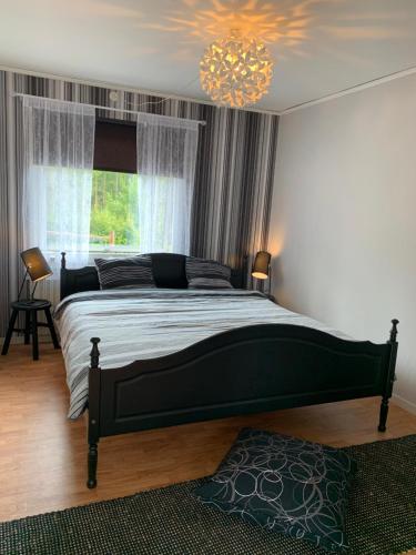 a bedroom with a large bed and a chandelier at Cozy house in Kosta center surrounding with Swedish nature in Kosta