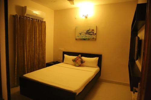 a small bedroom with a bed with white sheets and pillows at Kfour Apartment & Hotels Private Limited in Madurai