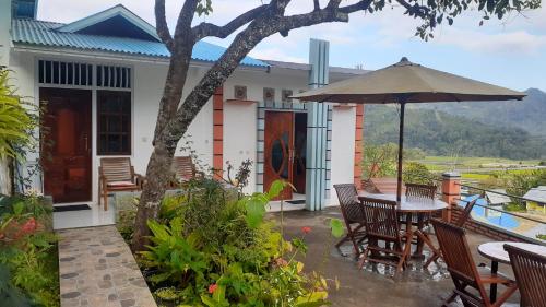 a patio with a table and chairs and an umbrella at Bintang Bungalow Tour & Travel in Kelimutu