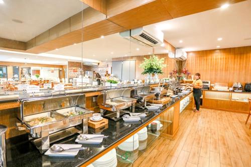 a restaurant kitchen with a long counter with food at Crystal Jade Hotel in Rayong