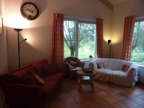 a living room with a couch and a clock on the wall at Boerderij "De Verwondering" in Goudriaan