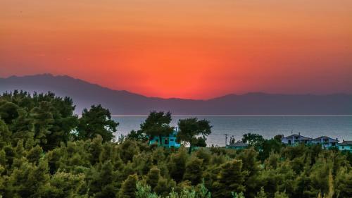 a sunset over the ocean with houses and trees at Sanidiamonds in Sani Beach