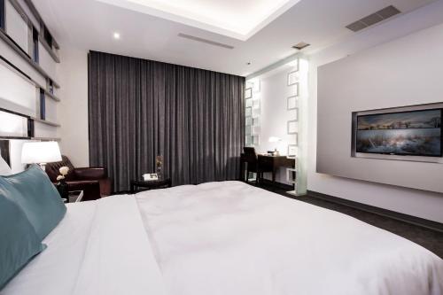 a bedroom with a large white bed and a desk at Duo Romance Hotel in Hualien City