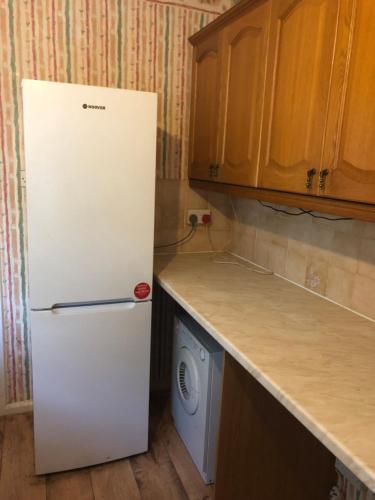 a white refrigerator in a kitchen with a washing machine at Relaxing double bedroom in Romford