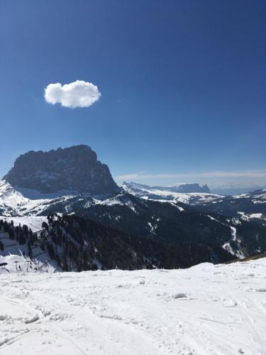 a view of a snowy mountain with a cloud in the sky at Arya Alpine Lodge in Selva di Val Gardena