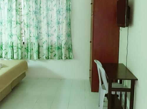 a room with a desk and a curtain and a table at Dindings Pantai Desair Apartment By DPD in Lumut