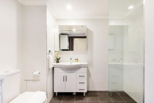 a white bathroom with a sink and a shower at 1 bdrm Surry Hills - Super central location -1012 ELZ in Sydney
