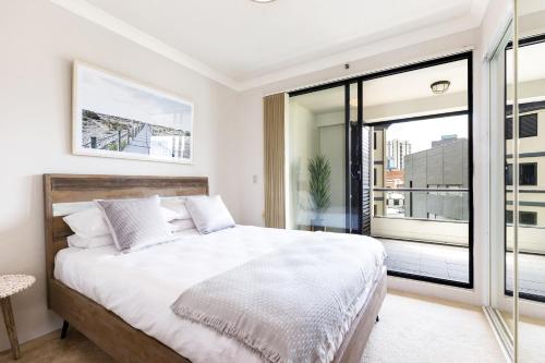 - une chambre avec un grand lit et un balcon dans l'établissement 1 bdrm Surry Hills - Super central location -1012 ELZ, à Sydney