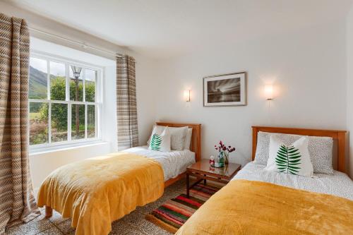 two beds in a room with a window at Enchanting,rustic, Dundurn Mill with stunning views and private river in Comrie