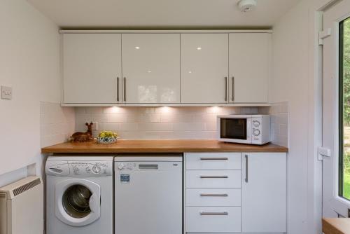 a kitchen with a washing machine and a microwave at Enchanting,rustic, Dundurn Mill with stunning views and private river in Comrie
