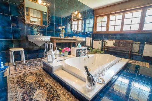 ein blau gefliestes Bad mit einer Badewanne und einem Waschbecken in der Unterkunft Villa Mazzucco in Ponte nellʼAlpi