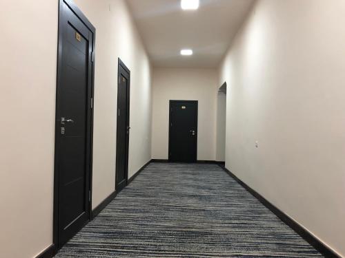 an empty hallway with two black doors and a carpet at Vanadzor Armenia Hotel in Vanadzor