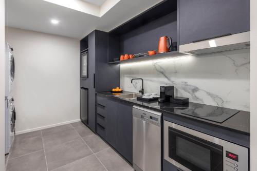 a kitchen with black cabinets and a counter top at Deco Hotel Canberra in Canberra
