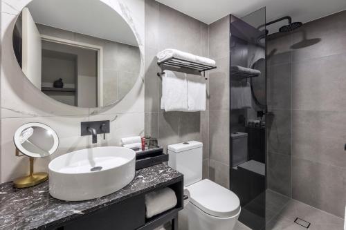 a bathroom with a sink and a toilet and a mirror at Deco Hotel Canberra in Canberra
