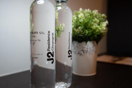 two bottles sitting on a table with a potted plant at J2 Residence Chiang Rai in Chiang Rai