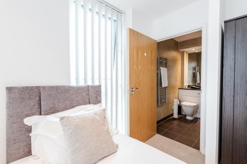 a bedroom with a bed and a bathroom with a toilet at EXCEL LONDON MAJESTIC APARTMENT in London