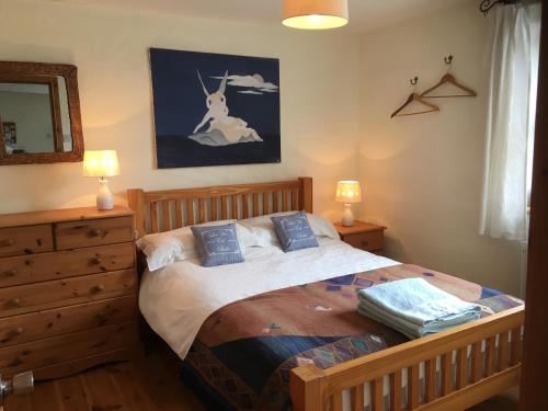 una camera con letto in legno e 2 cuscini blu di Restored School Master’s House a Valentia Island