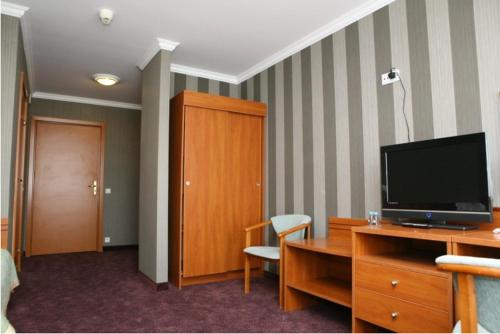 um quarto de hotel com uma televisão e uma secretária com uma cadeira em Hotel Złoty Młyn Polichno em Polichno