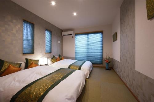 two beds in a hotel room with windows at Ixyz杜 in Nagoya