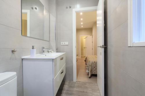 Un baño blanco con lavabo y espejo. en Conde de Gondomar 1, en Córdoba