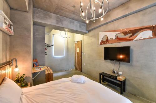 a bedroom with a white bed and a tv at Anping Wikid Design Hotel in Tainan