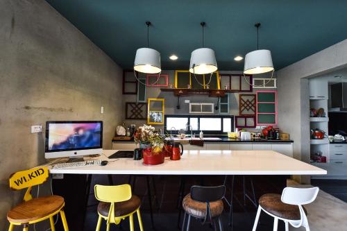 a kitchen with a desk with a computer and stools at Anping Wikid Design Hotel in Tainan