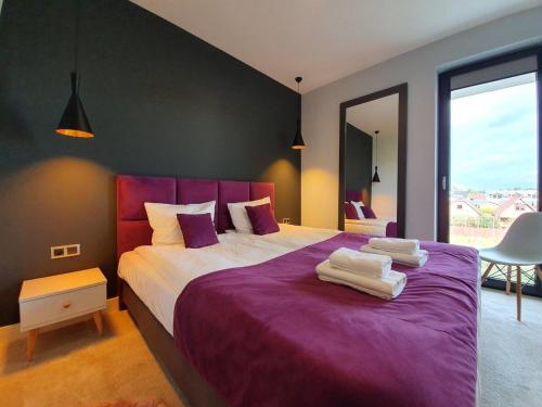 een slaapkamer met een paars bed met handdoeken erop bij Prywatny Apartament nr 32 w hotelu w Mielenku - 365PAM in Mielenko