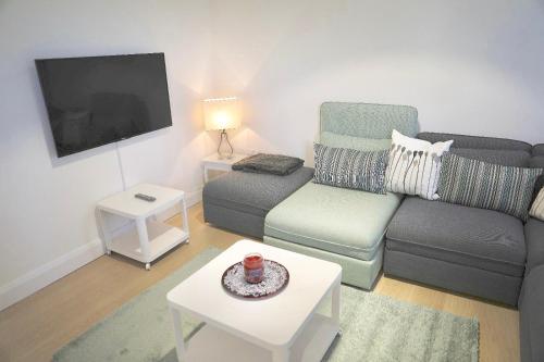a living room with a couch and a tv at Zenobia London Luxury Apartments in Finchley