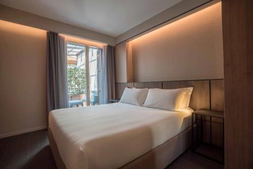 Be Mate Via Tivoli في ميلانو: غرفة نوم مع سرير أبيض كبير مع نافذة