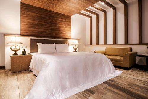 a bedroom with a large white bed and a chair at Duo Romance Hotel in Hualien City