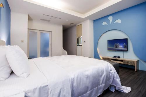a bedroom with a white bed and a blue wall at Duo Romance Hotel in Hualien City