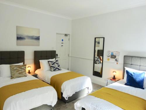 two beds in a room with white and yellow blankets at Reading Serviced Rooms in Reading