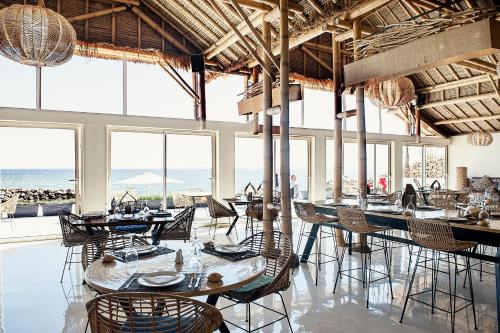 una sala da pranzo con tavoli, sedie e finestre di La Crique Nature & Spa a Dakhla