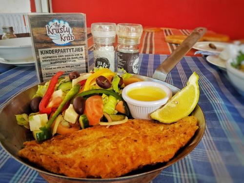 un tazón de comida con pescado y verduras y aderezo en Klein Plasie Lodge, en Hartswater