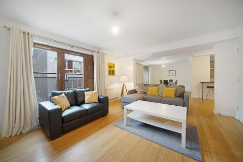 ein Wohnzimmer mit einem Sofa und einem Tisch in der Unterkunft 2 Bed Chic Apartment near Shoreditch & Liverpool St FREE WIFI & PARKING by City Stay Aparts London in London