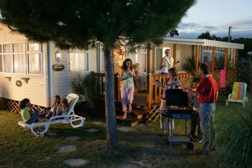 a group of people sitting on the porch of a caravan at Camping Officiel Siblu Le Bois Dormant in Saint-Jean-de-Monts