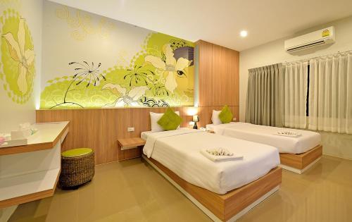 a bedroom with two beds and a painting on the wall at Tairada Boutique Hotel in Krabi town