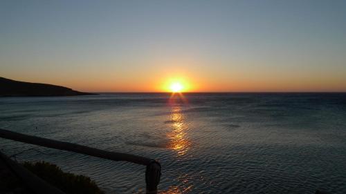 a sunset over the ocean with the sun setting at Coral Front Beach in Káto Zákros